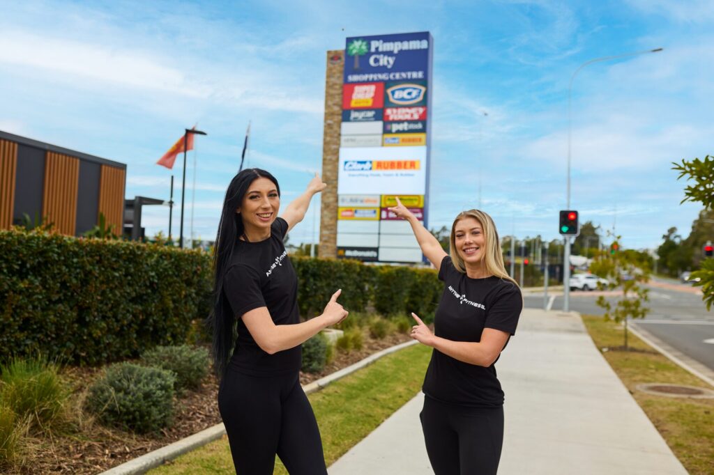 Pimpama team pointing at the shopping centre sign