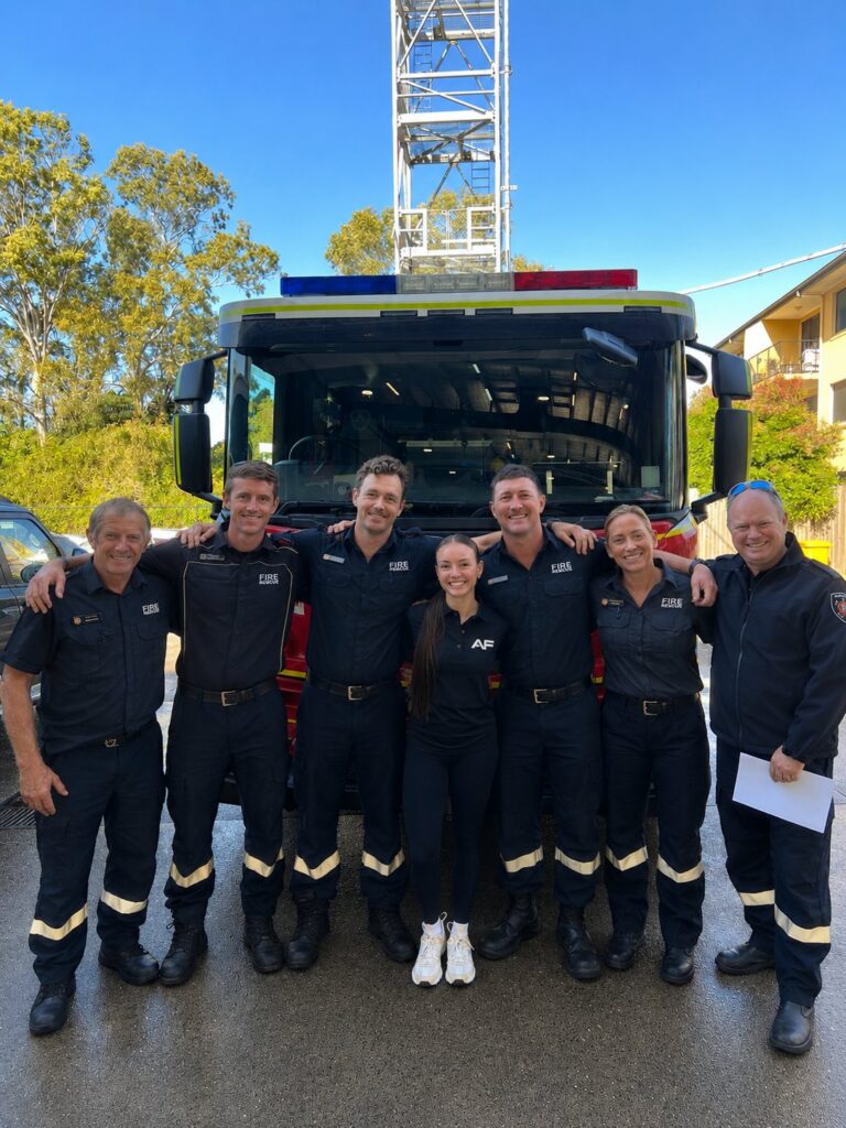 Firefighters and an Anytime Fitness team member in front of a fire truck